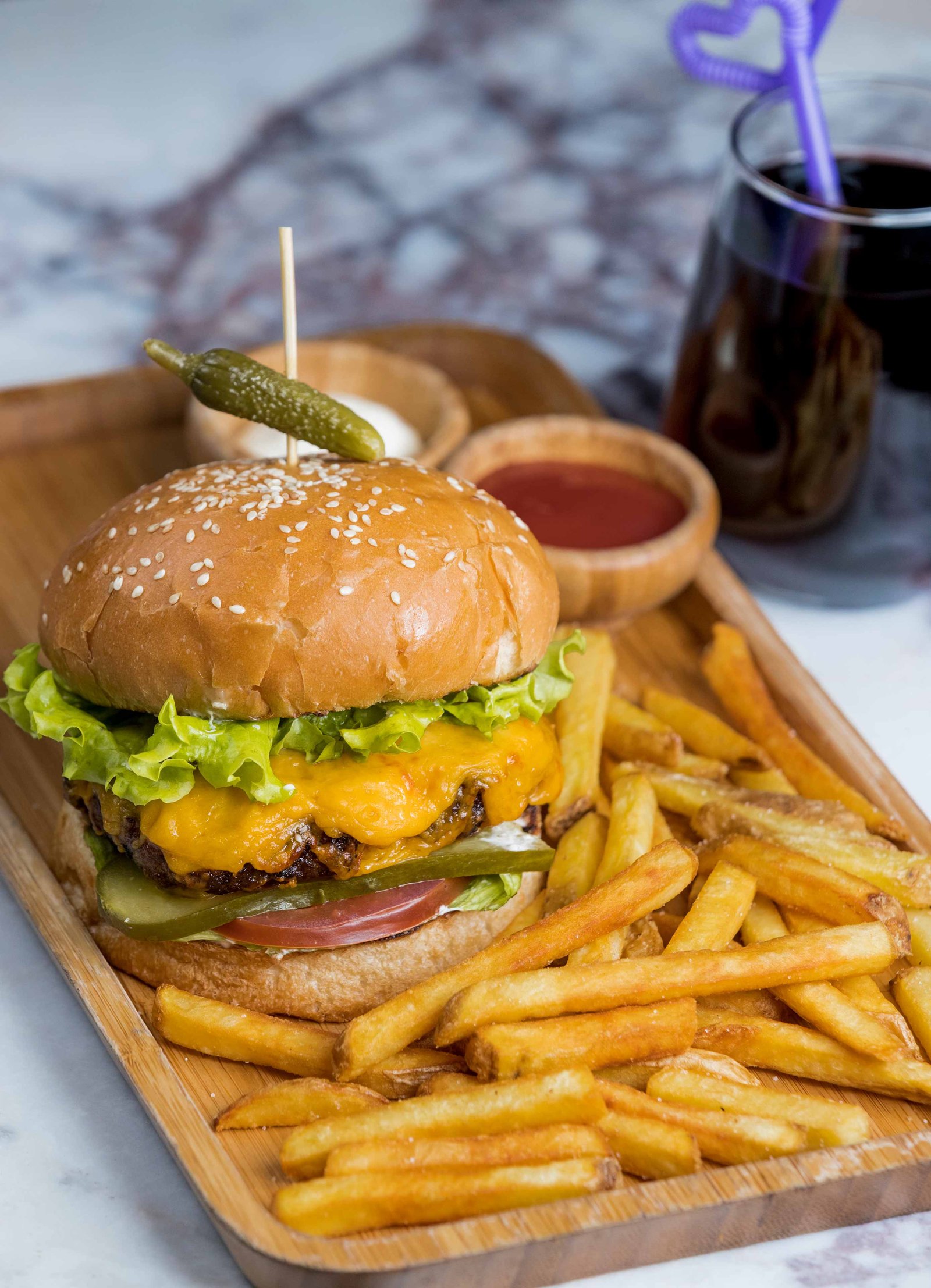 burger with fries red drink inside wooden platter